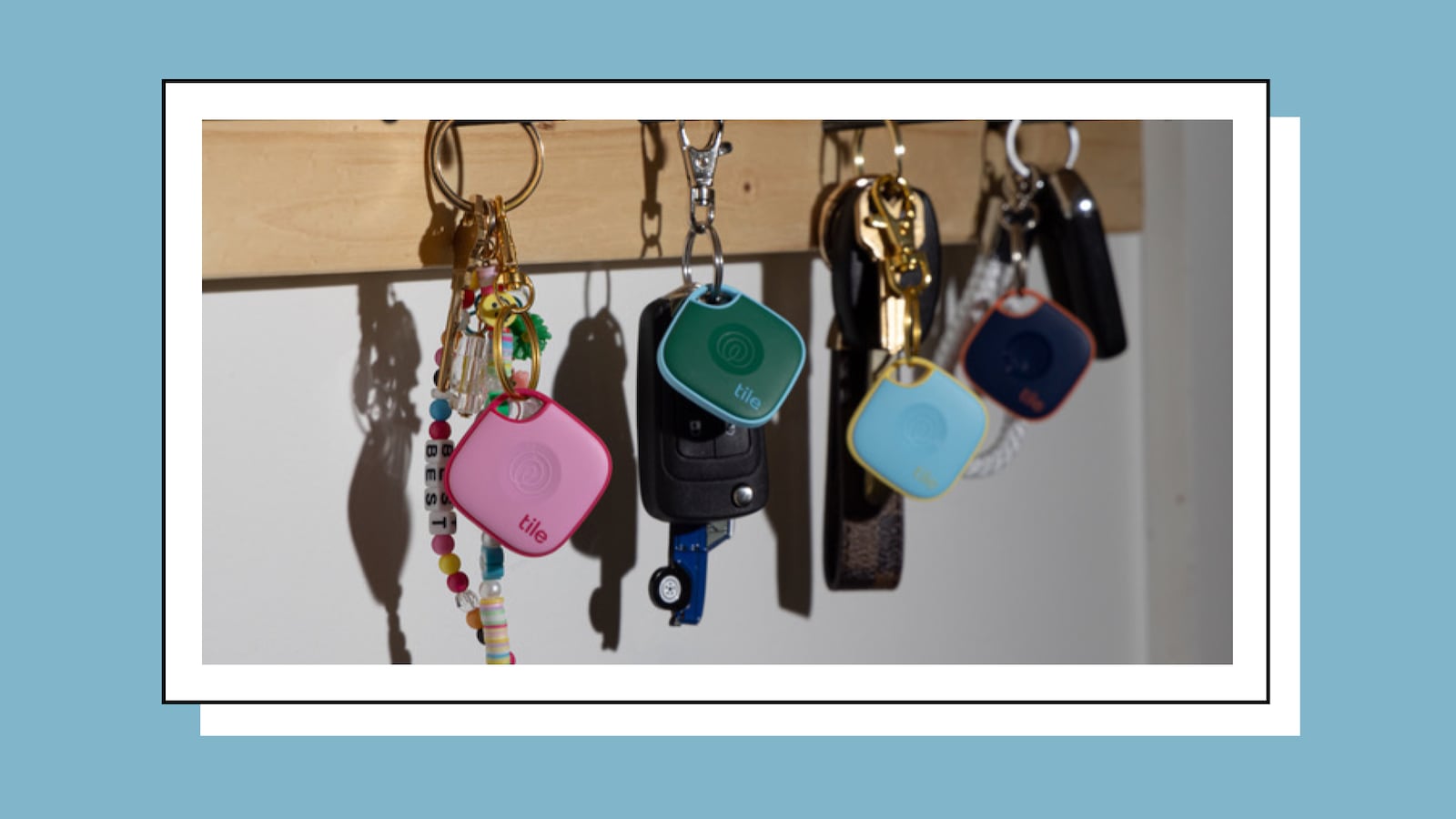 A photo of four sets of keys hanging on a wall, each on has a Tile Bluetooth tracker on them.