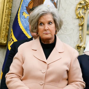 Susie Wiles stares at President Donald Trump during a press conference in the Oval Office.