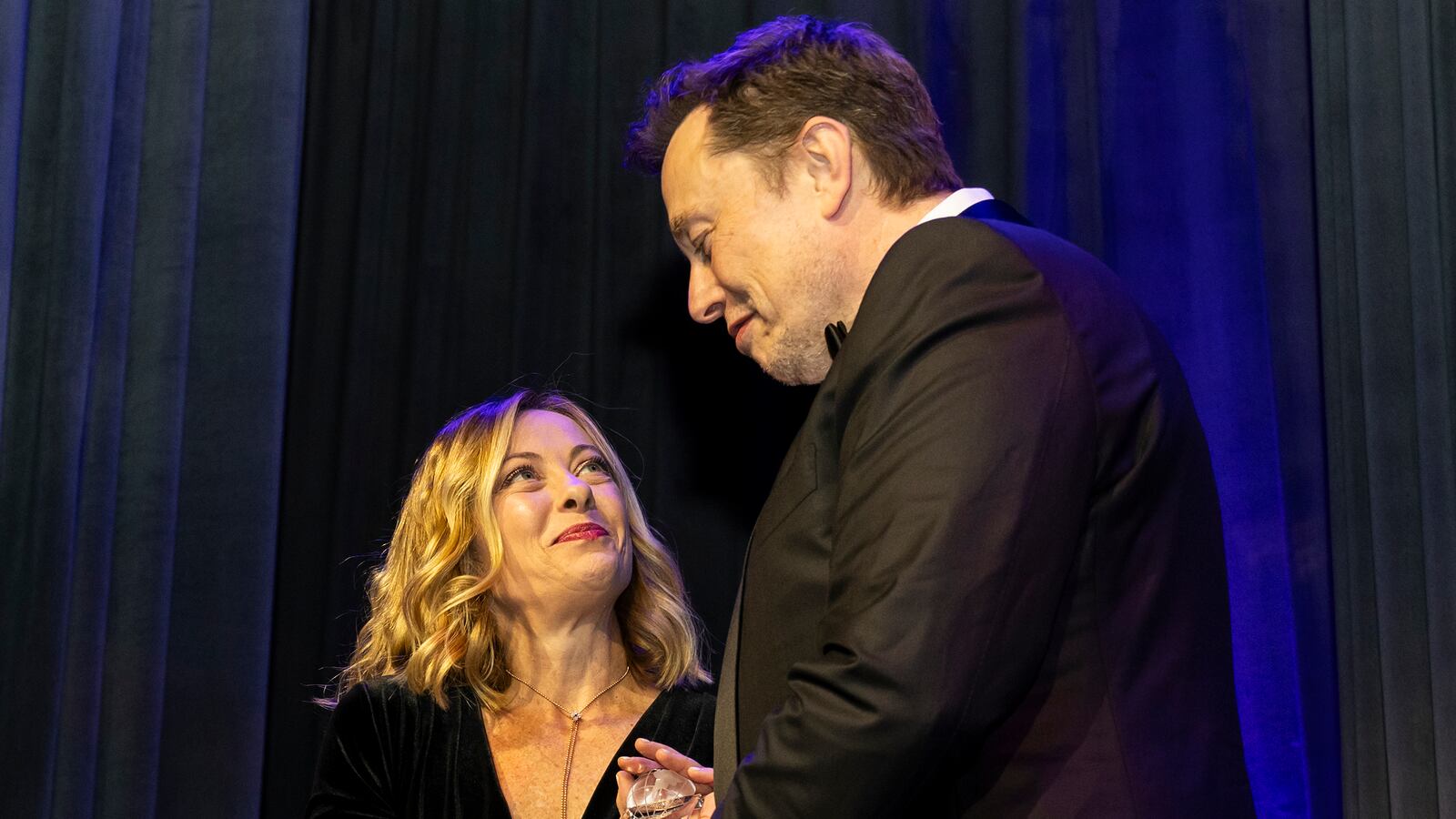 Elon Musk and Giorgia Meloni gaze into each other’s eyes on stage.