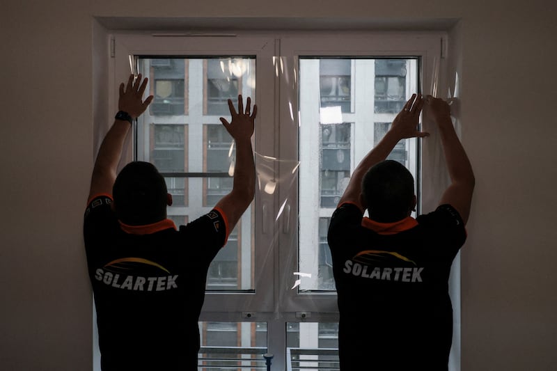 Employees of Russian firm Solartek install shatter-resistant film on a window in an apartment, as demand for blast protection rises following Ukrainian drone strikes during the Russia-Ukraine conflict, in Moscow, Russia, August 26, 2026.