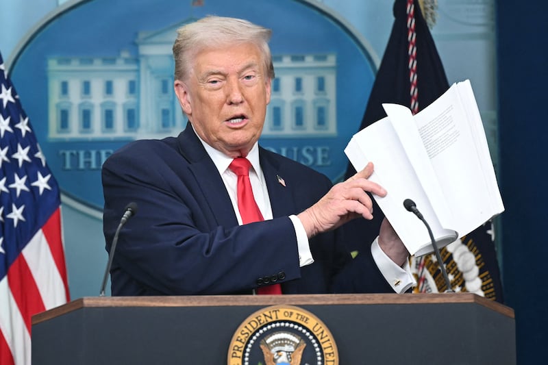 President Donald Trump holds up a booklet as he speaks during a briefing in the Brady Briefing Room of the White House in Washington, DC, on January 20, 2026.