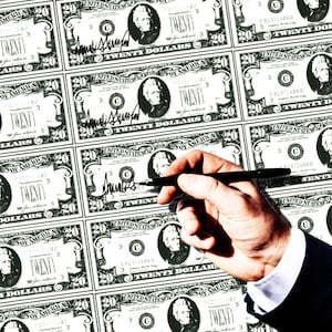 Donald Trump putting his autograph on money.