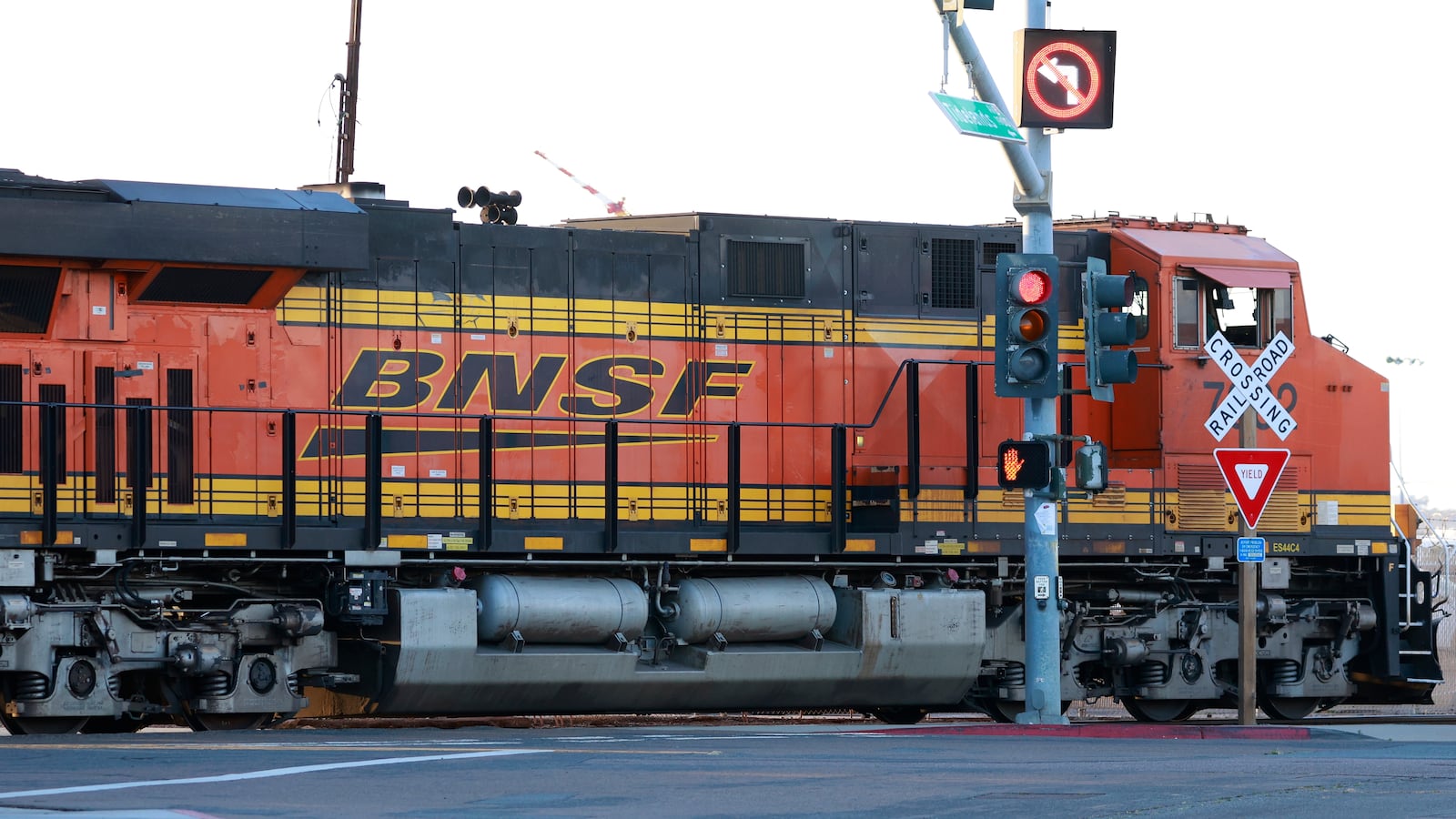 NATIONAL CITY, CALIFORNIA - APRIL 26: A BNSF Railway locomotive and train travels through an intersection at the National City Marine Terminal on April 26, 2025 in National City, California.