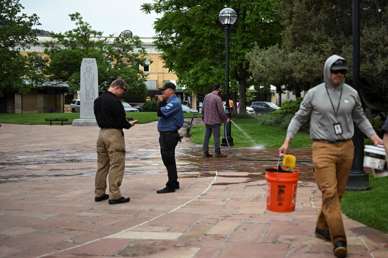 Workers clean the stone ground on Monday, a day after eight people were burned in a terrorist attack in Boulder, Colorado.