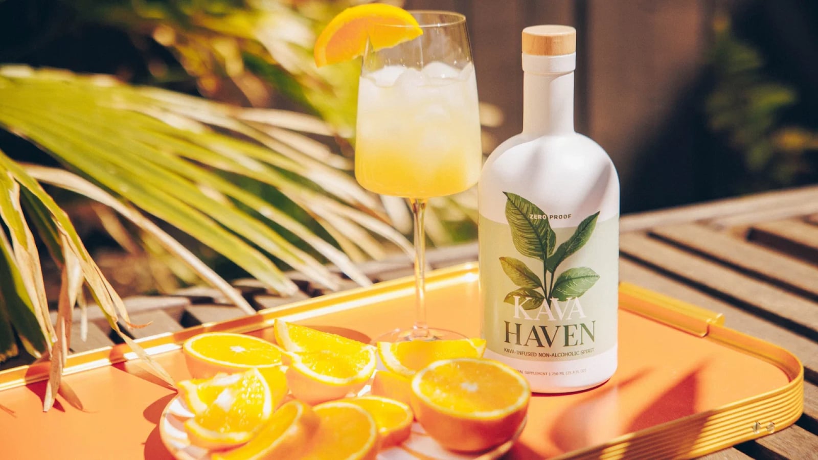 Kava Haven kava-infused non-alcoholic spirit bottle served on a tray with a citrus cocktail and fresh orange slices