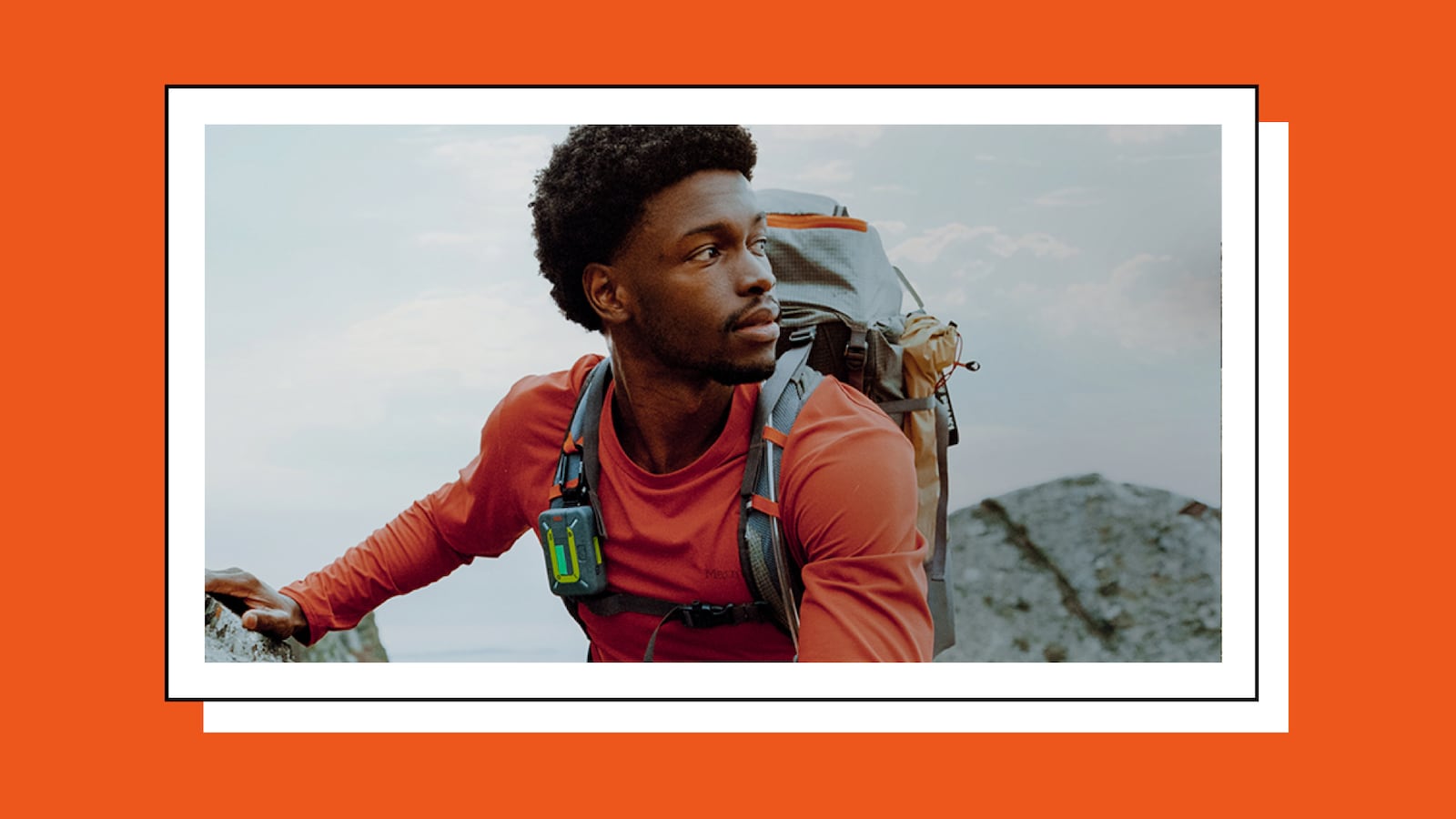 A man wearing a backpack and red shirt resting against a rock.