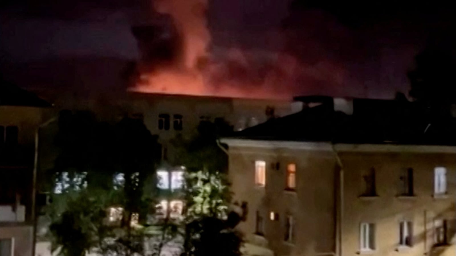 A plume of smoke is illuminated by a flash of light amid a drone attack in Pskov, Russia, in this still image obtained from social media video released August 30, 2023.