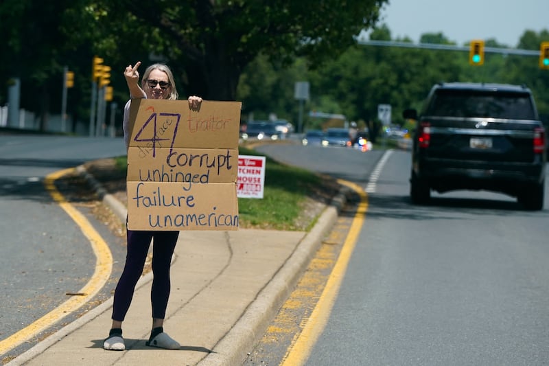 SENSITIVE MATERIAL. THIS IMAGE MAY OFFEND OR DISTURB A protester gestures as the motorcade carrying U.S. President Donald Trump travels to Trump National Golf Club in Sterling, Virginia, U.S., May 17, 2026. REUTERS/Elizabeth Frantz
