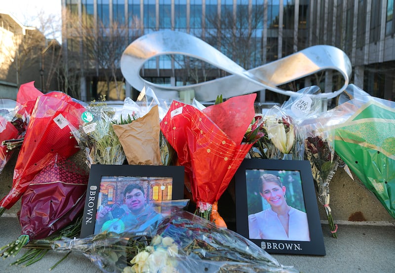 A photo of flowers and pictures gathered at a memorial for shooting victims MukhammadAziz Umurzokov, 18,  and Ella Cook, 19, outside of the Barus and Holley building on the campus of Brown University on December 16, 2025.