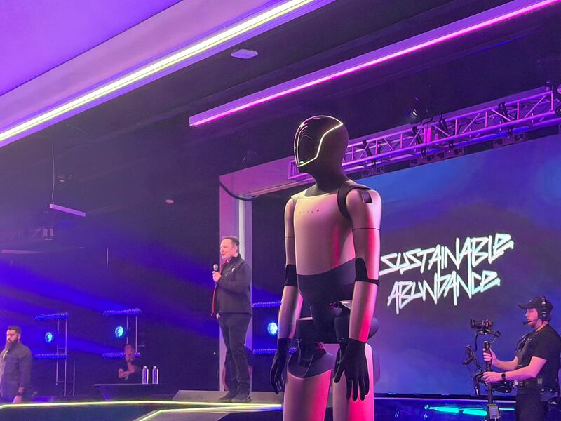 Elon Musk on stage, with the robot he danced with to his right.