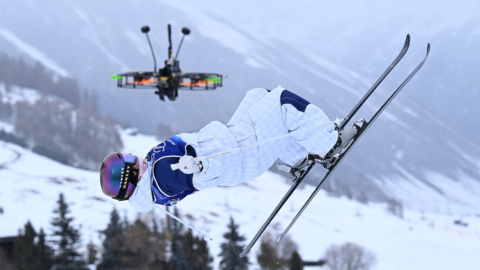 A broadcast drone hovers as Britain's Makayla Gerken Schofield competes in the freestyle skiing women's moguls qualification 1 during the Milano Cortina 2026 Winter Olympic Games