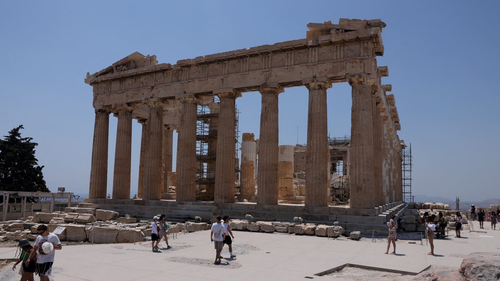 Visitors walk near the Parthenon temple atop the Acropolis hill, during a heatwave in Athens, Greece.