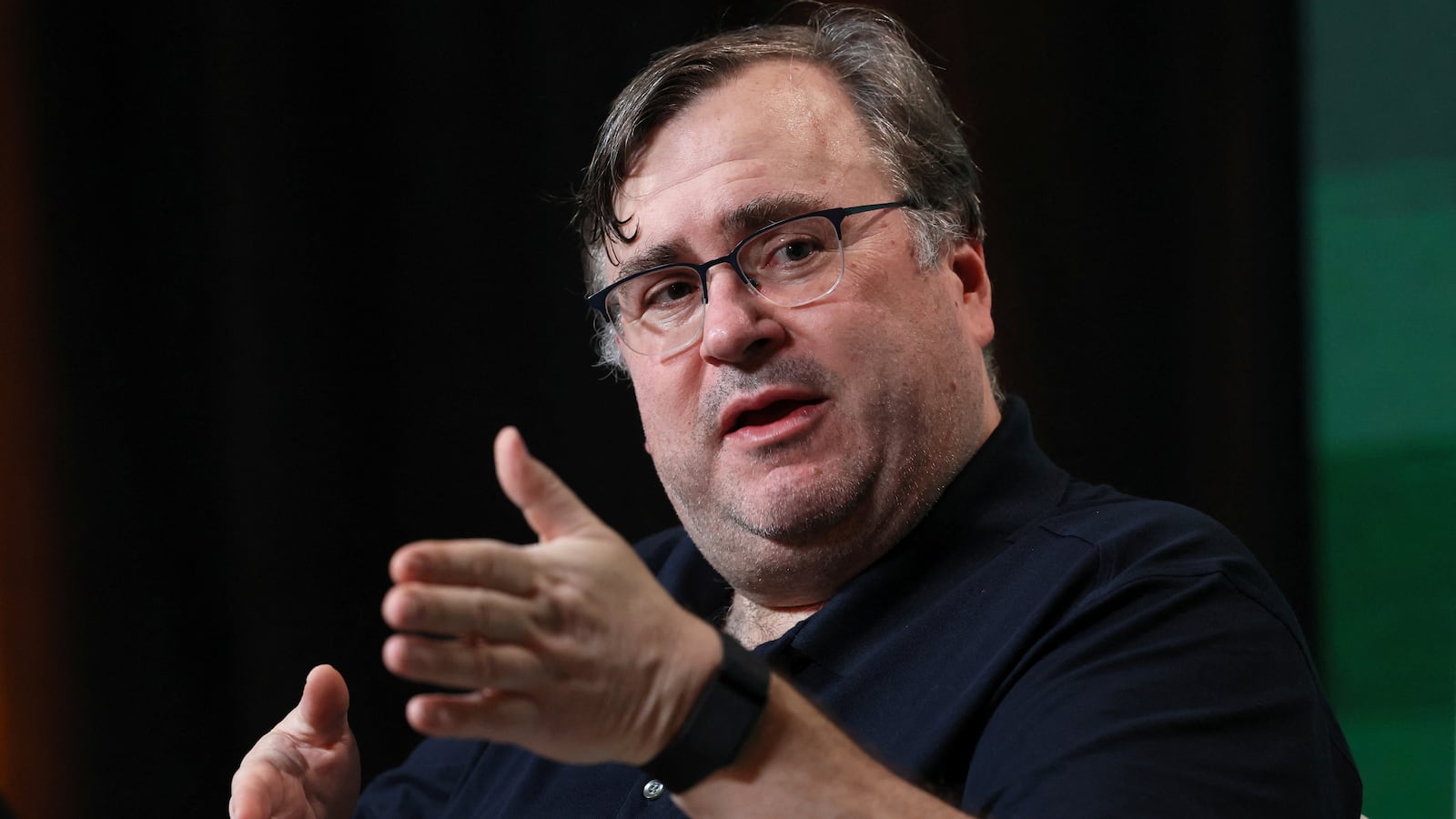 Reid Hoffman speaking on stage at an event.