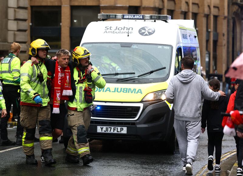 A Liverpool fan is supported by first responders after a car rammed into parade-goers on Monday.