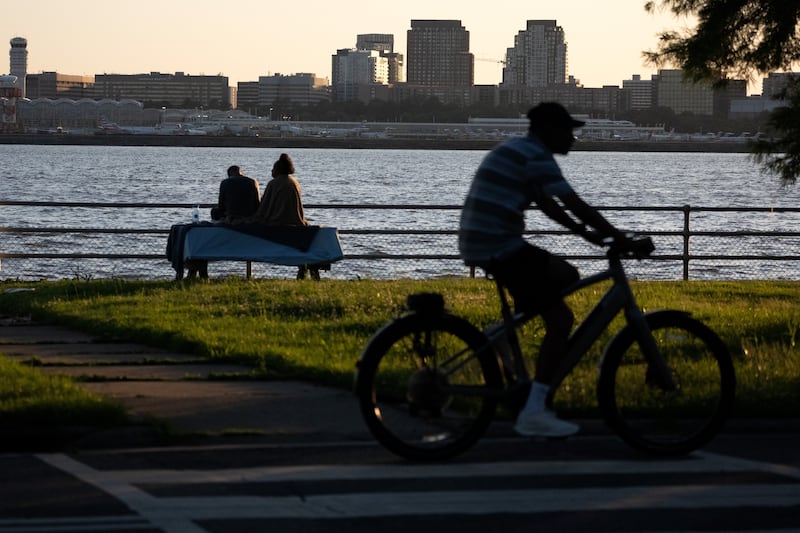 WASHINGTON, DC - MAY 26: People look out over the Potomac River as cyclists pass on Ohio Dr. SW, the road that rings Hains Point, on Thursday, May 28, 2026 in Washington, D.C. Reagan National Airport is visible at rear. (Photo by Peter W. Stevenson/The Washington Post via Getty Images)