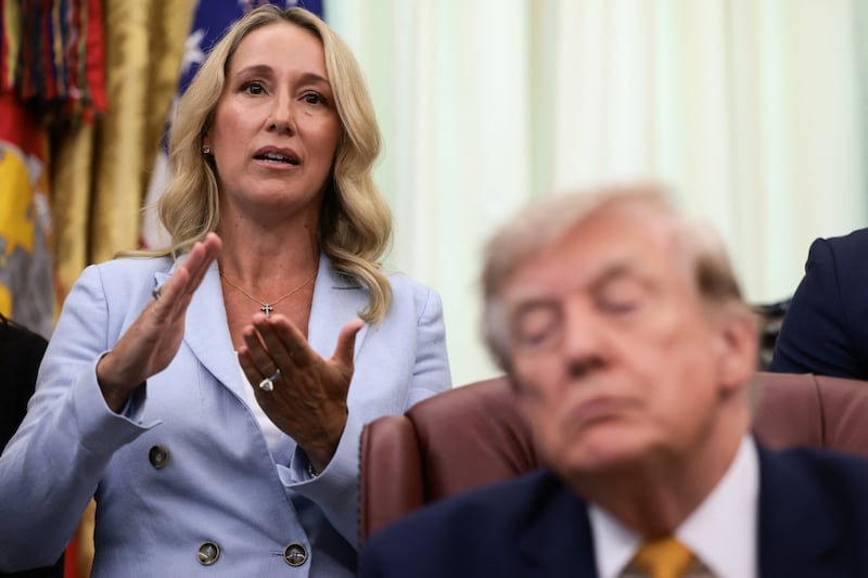 Jennifer Rauchet, wife of Secretary of Defense Pete Hegseth, speaks as President Donald Trump listens during an event to sign an executive order establishing the President's Military Spouse Commission to be chaired by Rauchet in the Oval Office at the White House in Washington, D.C., on August 3, 2026.