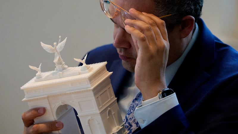 Member of the Fine Arts Commission inspects a model of President Donald Trump's proposed triumphal arch.