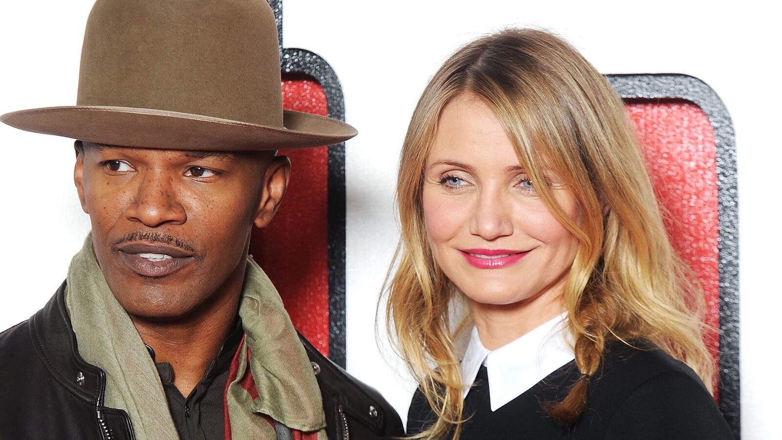 A Black man and white blonde woman stand together on a red carpet.