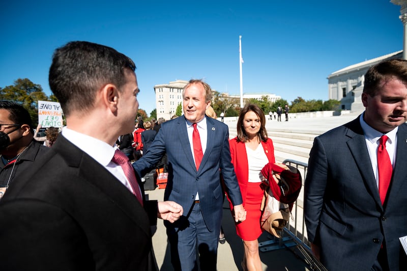 Texas Attorney General Ken Paxton and his wife Angela leave after speaking to pro-life activists outside the Supreme Court after the court heard two challenges to Texas' new abortion law on Monday, Nov. 1, 2021.