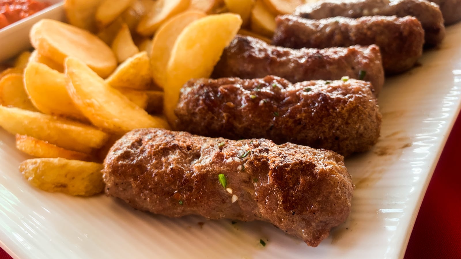 Traditional balkan grilled meat called cevapcici is seen on a restaurant table