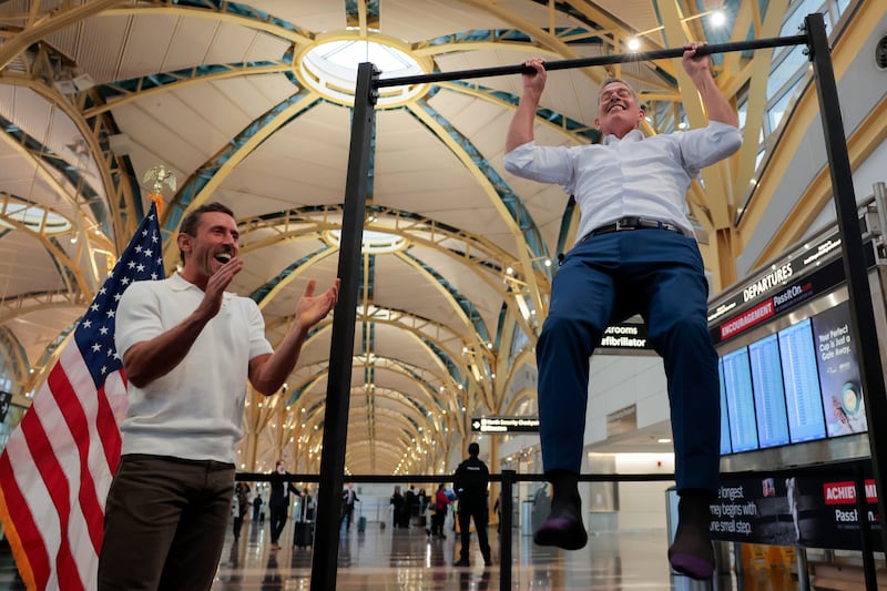 Influencer Dr. Paul Saladino watches U.S. Transportation Secretary Sean P. Duffy do pull-ups after a press conference discussing the launch of the "Make Travel Family Friendly Again" campaign at Ronald Reagan Washington National Airport