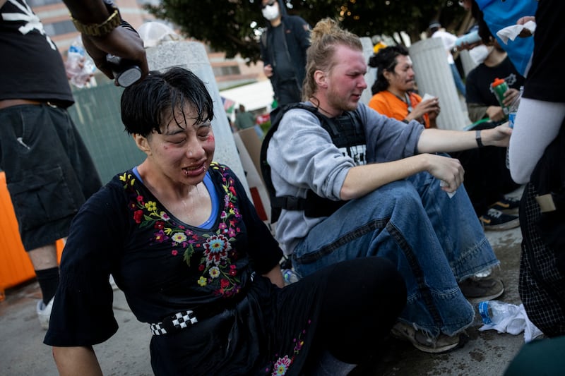 Three people side on a kerb as their treated for the effects of tear gas.