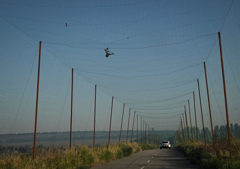 Members of the police evacuation unit drive along a road covered with an anti-drone net as a Russian FPV drone is stuck in it, during an evacuation from the frontline village, amid Russia's attack on Ukraine, in Zaporizhzhia region, Ukraine August 20, 2026. REUTERS/Stringer     TPX IMAGES OF THE DAY
