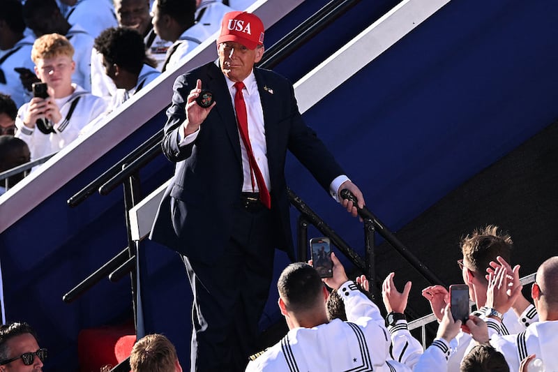 US President Donald Trump holds up an object after delivering remarks during the US Navy's 250th anniversary celebration, "America's Navy 250: Titans of the Sea - A Salute to the Fleet", at Naval Station Norfolk Pier 14 in Norfolk, Virginia on October 5, 2025.