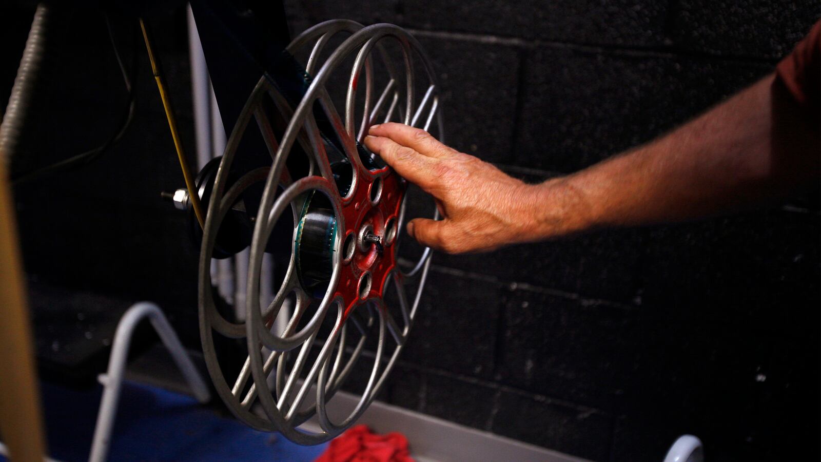 Projectionist Bill Hulbert tightens a 35mm film reel in a movie projector while working at the Black River Drive-In theater