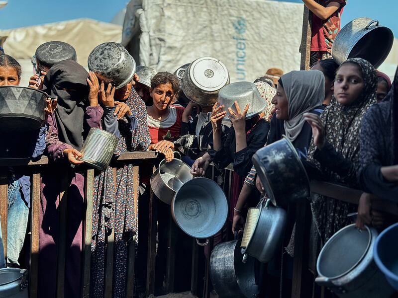 Displaced Palestinians wait in long lines for a meal.