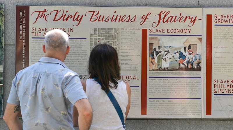 PHILADELPHIA, PENNSYLVANIA - AUGUST 9: Tourists inspect a display entitled 'The Dirty Business of Slavery' at the President's House on August 9, 2025 in Philadelphia, Pennsylvania. Around a dozen different exhibits and displays in Independence National Historic Park are under review by the National Park Service for potential removal or editing on September 17. The initiative to eliminate materials deemed disparaging to the Founding Fathers or the legacy of the United States is part of an executive order issued by Donald Trump in March. (Photo by Matthew Hatcher/Getty Images)