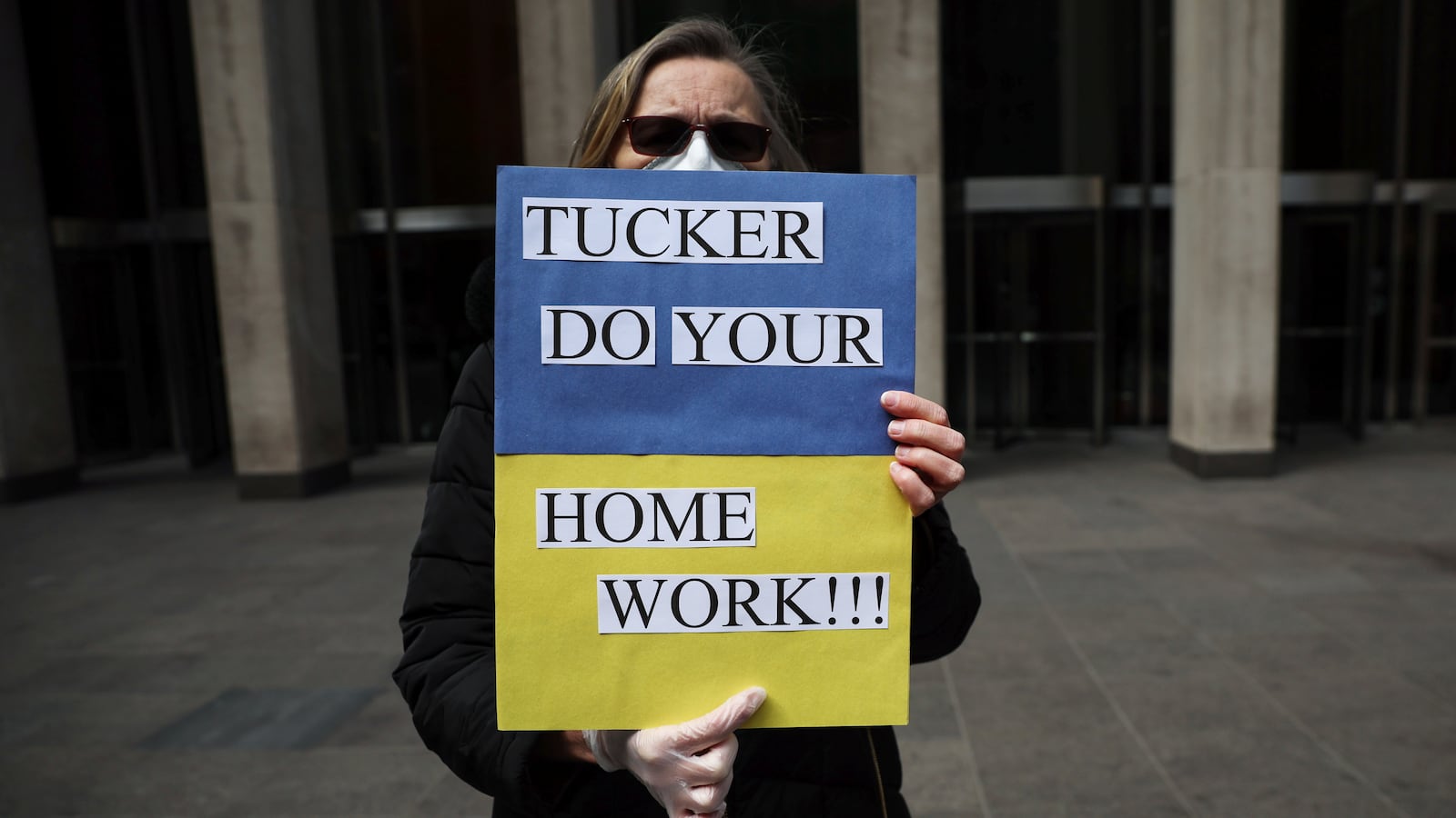 A woman stands outside the News Corp. and Fox News building protesting against Fox News and conservative political commentator Tucker Carlson’s coverage of the Russian invasion of the Ukraine in New York City.