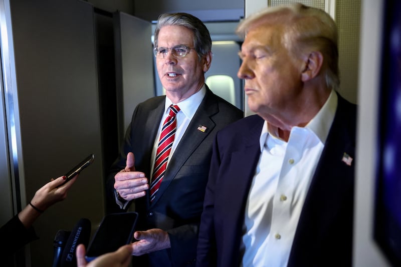 U.S. Treasury Secretary Scott Bessent speaks to reporters as U.S. President Donald Trump stands next to him aboard Air Force One en route to Tokyo, Japan, for the second stop on his Asia tour, October 27, 2025. REUTERS/Evelyn Hockstein