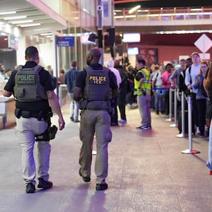 Ice agents walk through a long line of travelers at Atlanta Hartsfield-Jackson International Airport