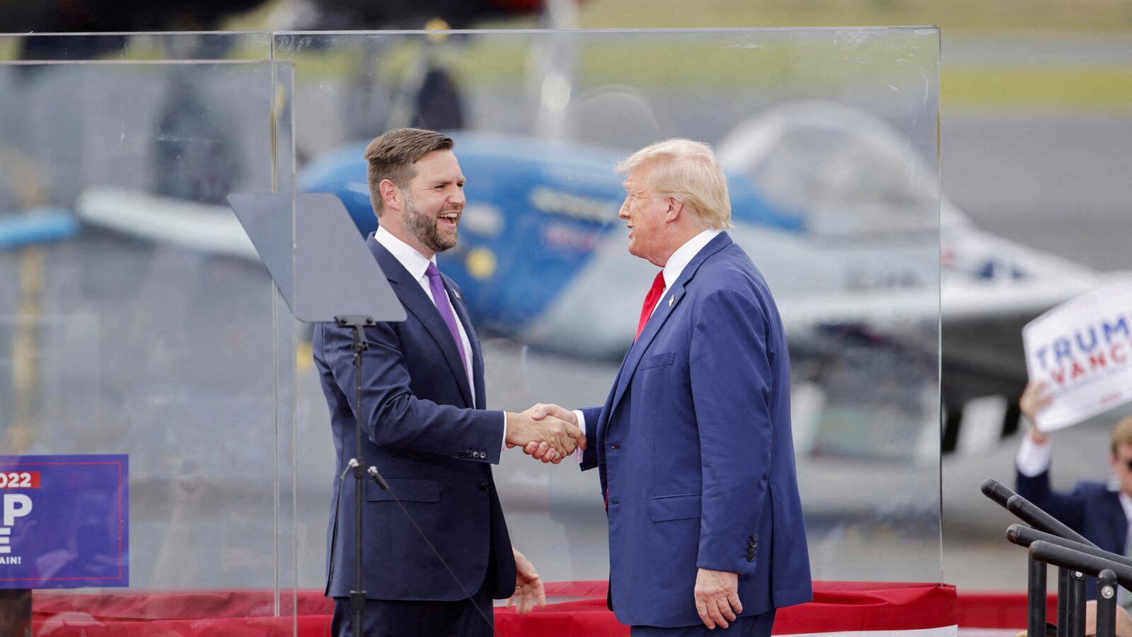 Republican presidential nominee Donald Trump and his vice presidential nominee JD Vance shake hands in a bulletproof 'glass house' during a rally in Asheboro, North Carolina on August 21, 2024.