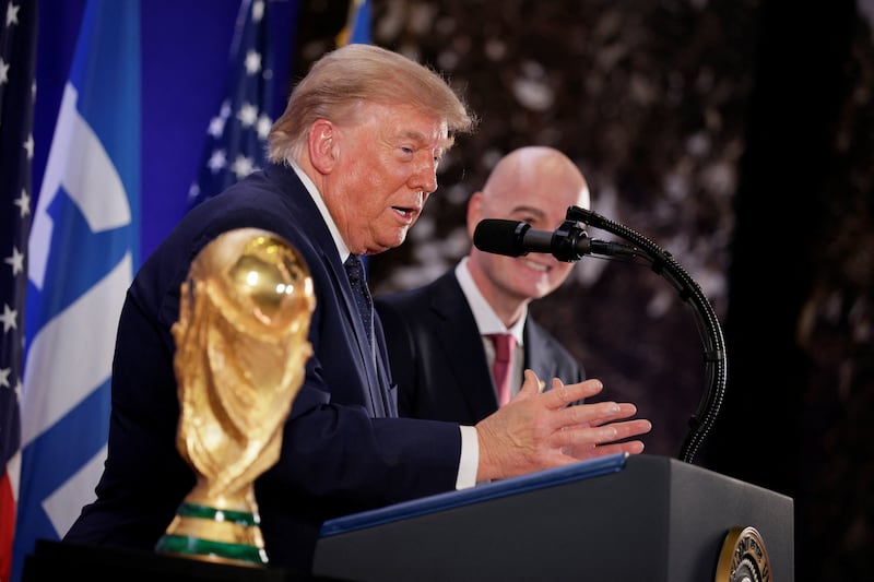 Trump and Infantino speak next to the World Cup trophy at a FIFA reception at Trump Tower.