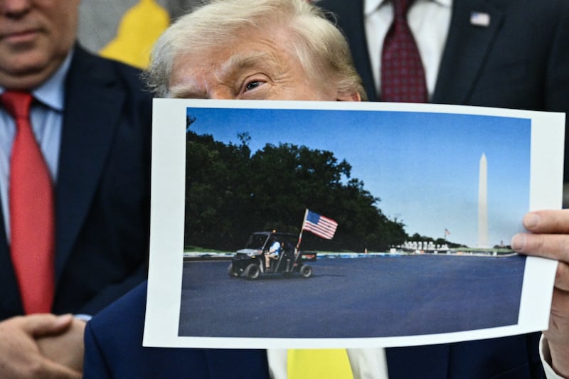 President Donald Trump holds a picture of the newly resurfaced Reflecting Pool on the National Mall as he speaks in the Oval Office of the White House in Washington, DC on June 4, 2026.