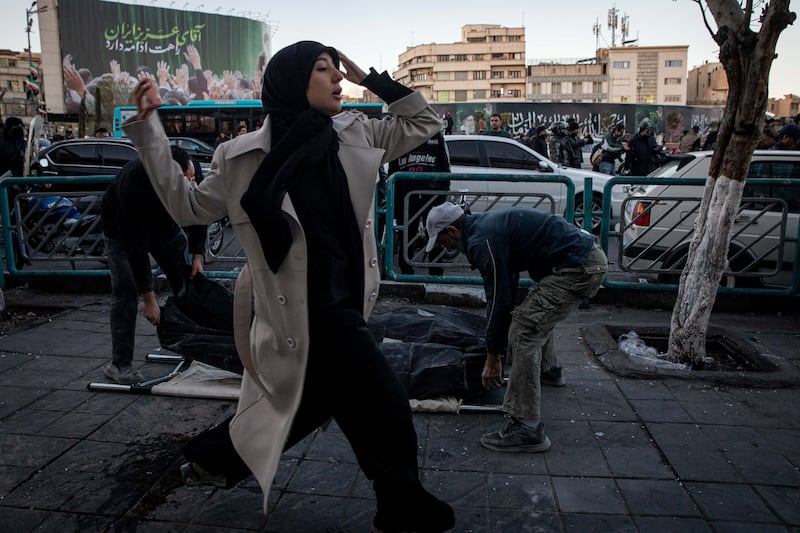 A woman runs past people placing casualties of an Israel and U.S. strike on a police station, on the ground, in Tehran, Iran, March 3, 2026. Majid Khahi/ISNA/WANA (West Asia News Agency) via REUTERS ATTENTION EDITORS - THIS PICTURE WAS PROVIDED BY A THIRD PARTY