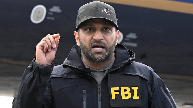 FBI Director Kash Patel stands at a lecture in between two law enforcement officials at a news conference.