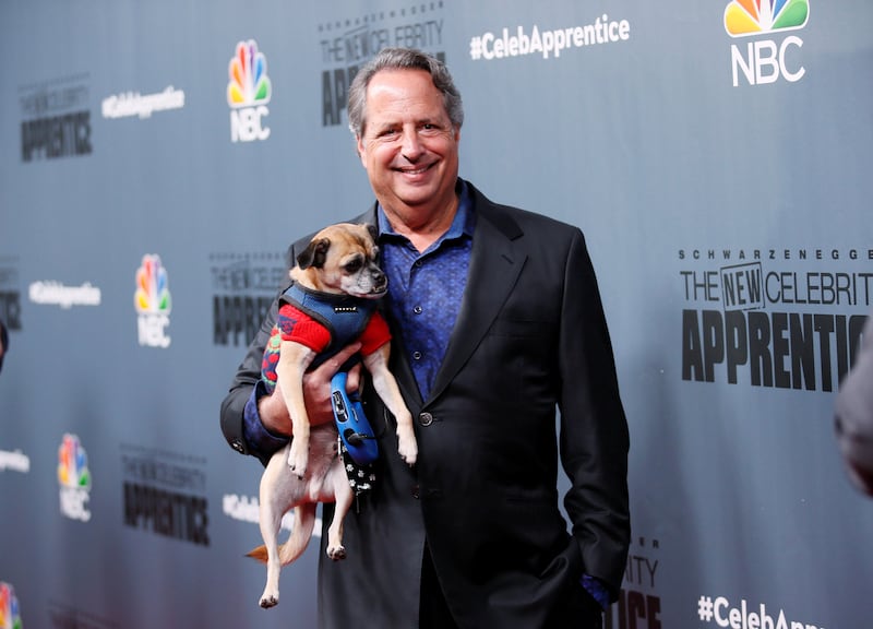 Jon Lovitz poses with a dog after a panel for "The New Celebrity Apprentice." REUTERS/Danny Moloshok