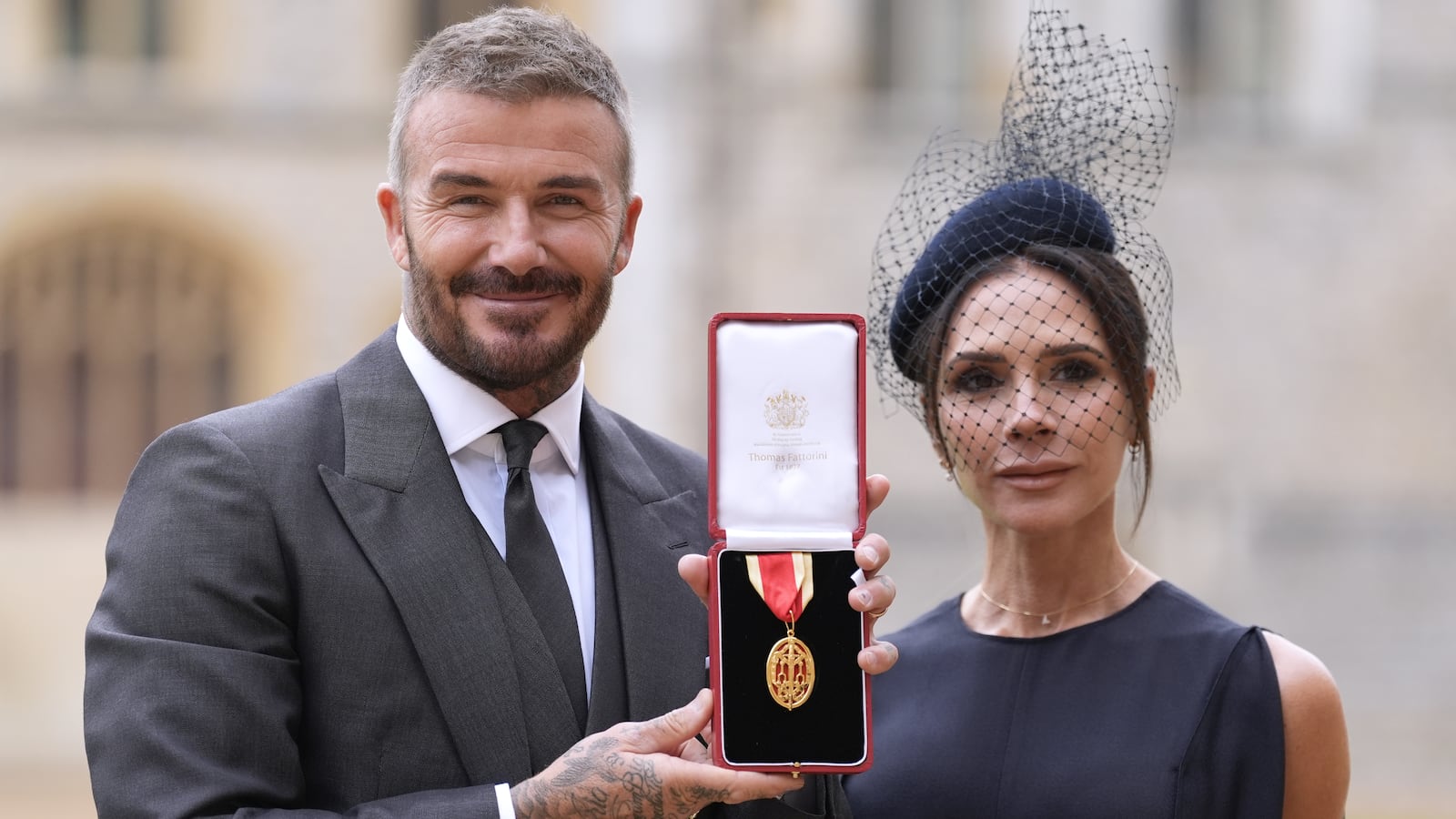 Sir David Beckham poses with his wife Lady Victoria after he was made a Knight Bachelor