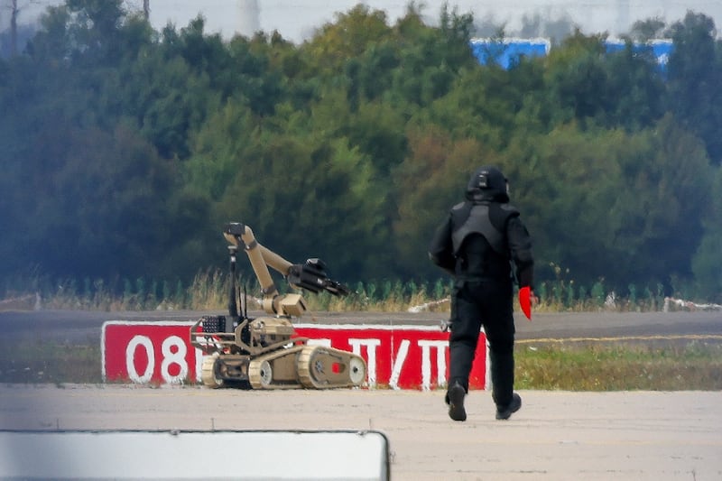 A police officer in protective clothing walks next to an explosive-disarming robot (EOD) at Leipzig/Halle Airport in Schkeuditz, Germany, August 5, 2026, after the police said explosives experts examined a drone found near a runway, and after a DHL cargo aircraft hit an unknown object as it was climbing away from the airport overnight, prompting an unscheduled landing in Hanover, according to a source familiar with the incident. REUTERS/Axel Schmidt