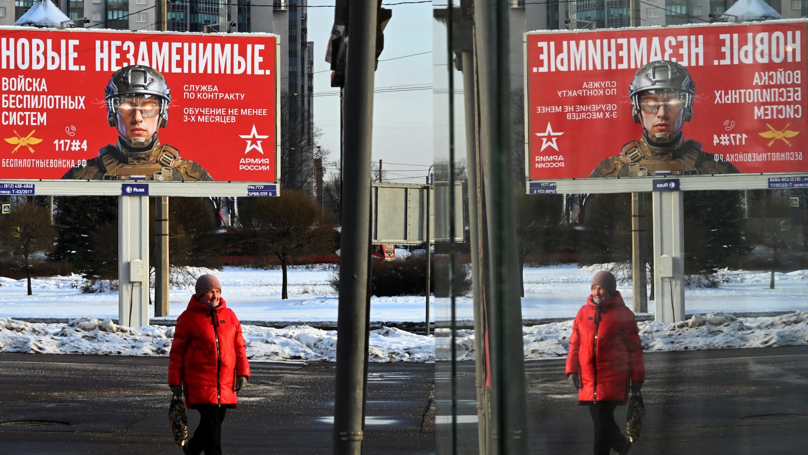 A woman walks past a billboard advertising for contract based military service in the Russian army's unmanned systems units with the slogan 'New. Irreplaceable.' in Saint Petersburg on January 24, 2026. (Photo by Olga MALTSEVA / AFP via Getty Images)