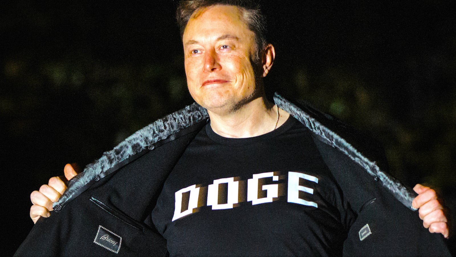 Elon Musk opens his jacket to show his shirt that says “DOGE” as he walks into the White House after landing in Marine One on the South Lawn.