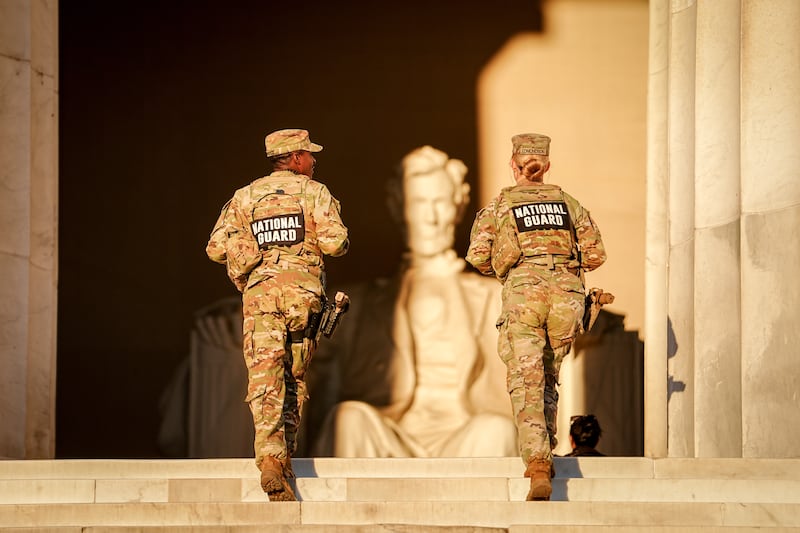 US National Guard soldiers walk up the steps to the Lincoln Memorial in the early morning.