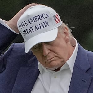 U.S. President Donald Trump holds his hat as he walks on the South Lawn of the White House in Washington, D.C., U.S., May 25, 2025.
