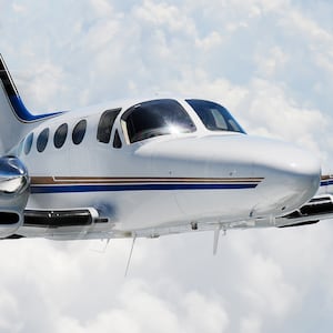Cessna 421 turbine conversion small twin engine charter airplane in flight with clouds in the background.