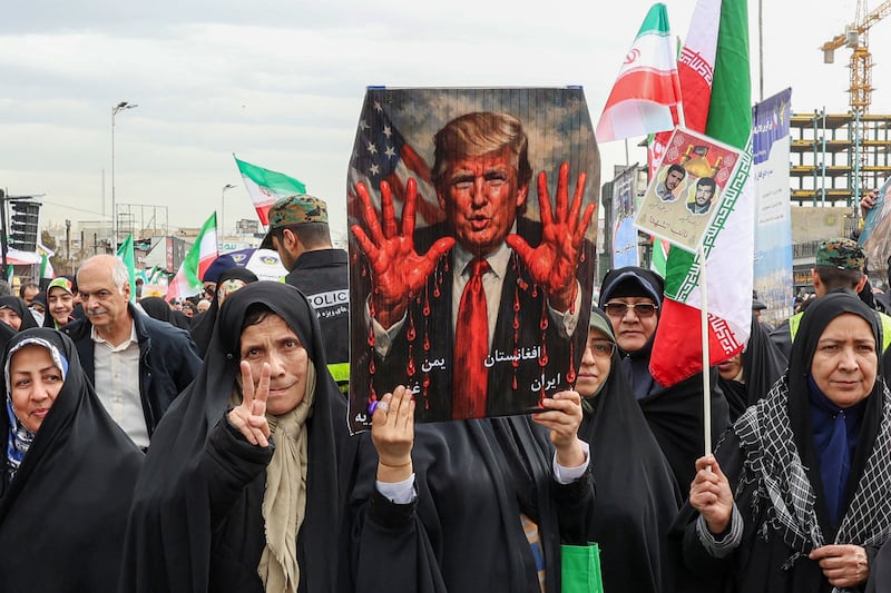 Women march with a sign depicting US President Donald Trump with bloodied hands in Tehran on February 11, 2026,