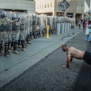 A man does push-ups in front of US Marines and Customs and Border Protection officers.