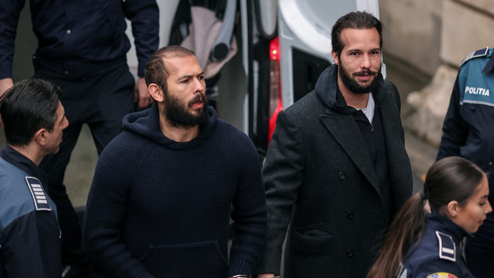 Andrew Tate and his brother Tristan are escorted by police officers inside the headquarters of the Bucharest Court of Appeal, in Bucharest, Romania, Feb. 27, 2023.